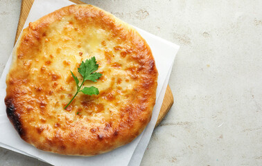 Delicious Megrelian khachapuri with parsley on grey table, top view. Space for text