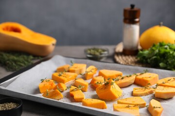 Pieces of fresh pumpkin with thyme and other spices on table, closeup