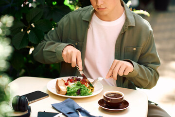 Young man enjoys a meal outside at a modern cafe, savoring fresh flavors