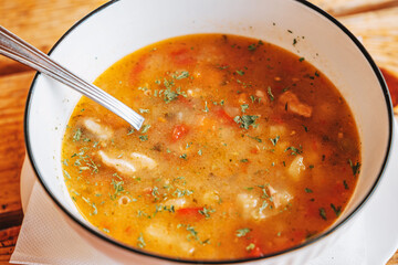 Hearty goulash stew with tender meat and vegetables in a white bowl, warm comfort food served on rustic wooden table