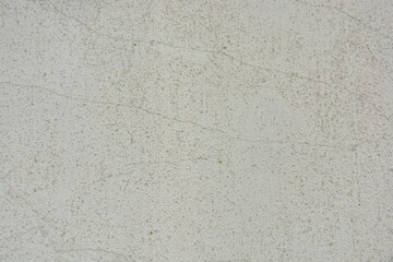 Construction and renovation work, plastering load-bearing street walls in sunlight. The white walls are coated with rough street primer with long micro-cracks throughout the surface and background.