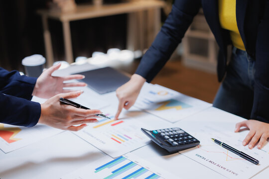 Business colleagues collaborating on a project, analyzing financial reports, charts, and graphs during an important meeting, focusing on strategic planning and data analysis