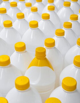 Array of white plastic bottles with yellow caps, one bottle unique