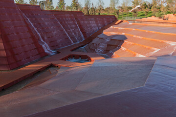 Water amphitheater or canyon in Krasnodar's city park or Galitsky Park. Striking architectural landscape features cascading red-colored walls and geometric water channels. Fall 2025.