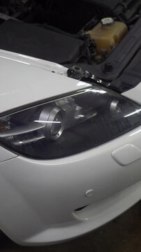 The front right headlight of a white car. Foggy headlight. A leaky headlight.