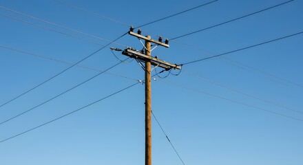 Wooden utility pole with high-voltage wires against a clear blue sky
