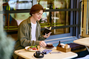 Young man enjoys a meal and writes in a cafe amid casual atmosphere