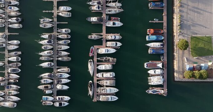 Top down aerial view of the Albuufeira marina at sunset, showing sailboats and yachts neatly moored in parallel rows, Algarve region, Portugal. 