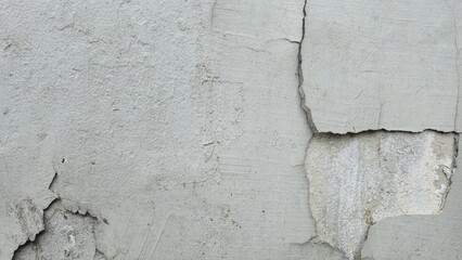 Gray cement wall surface with cracks and peeling paint revealing inner layers, showing rough...