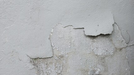 Gray cement wall surface with cracks and peeling paint revealing inner layers, showing rough...
