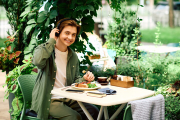 Young man enjoys delicious meal in modern cafe surrounded by greenery and nature