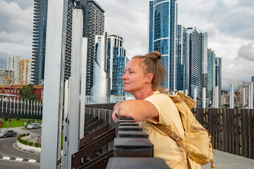 Woman enjoying the city skyline view from a modern bridge in a bustling urban setting