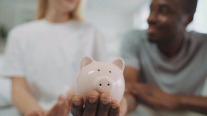 Save money in piggy bank, closeup of hand of african man, lady putting coins. Happy multiracial married couple holding savings in moneybox, young people thinking of future family life, economy