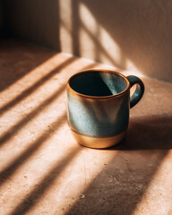Single ceramic mug on pastel table with dramatic shadows