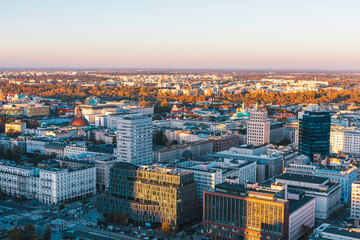 Aerial view of Warsaw, Poland city center at sunset, with mix of historical and modern buildings in warm light. Vistula River valley and part of the city densely built urban landscape