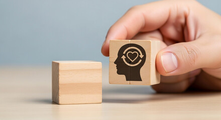 Hand places wooden block with heart symbol within head silhouette symbolizing emotional intelligence and mental well being