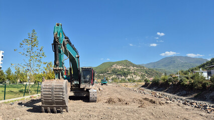 heavy excavation work agains a mountainous backdrop. Industrial earthmoving in a sceninc natural environment