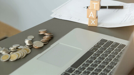 Tax preparation with coins, laptop, and documents on office desk, symbolizing financial planning and accounting stress