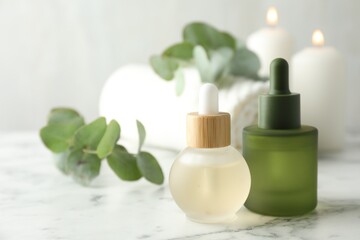 Beautiful spa composition with essential oils and eucalyptus on white marble table, closeup