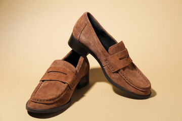 Pair of stylish brown shoes on beige background, closeup