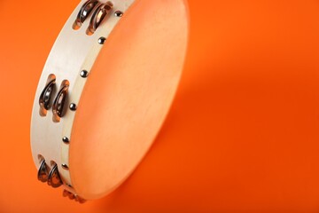 Tambourine on orange background, closeup. Space for text