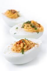 Homemade hard Boiled Deviled Eggs garnished with herbs isolated on white background