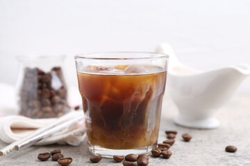 Tasty iced coffee with milk and beans on light table, closeup