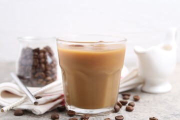 Tasty iced coffee with milk and beans on light table, closeup
