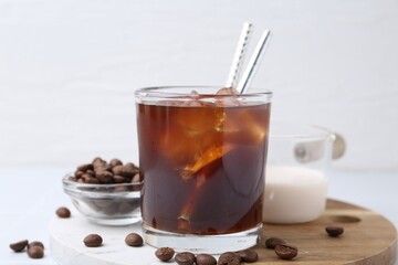 Tasty iced coffee, milk and beans on white table, closeup