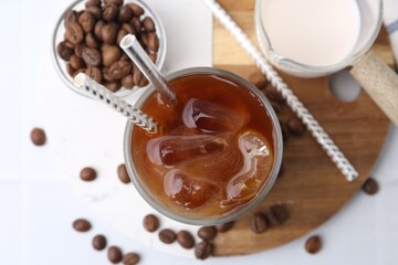 Tasty iced coffee with milk and beans on white table, flat lay