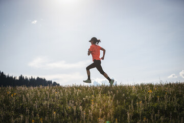 Female runner running on the high altitude grassland mountain top