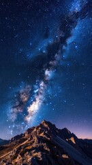 A vibrant Milky Way galaxy glows in the night sky above a rugged mountain peak