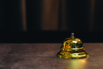 Service bell concept. Polished Brass Service Bell on a Dark Table Reflecting Soft Light in a Hospitality Setting for Customer Engagement