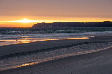 Golden sunset over sea and sandy beach. Peaceful evening by the shore.