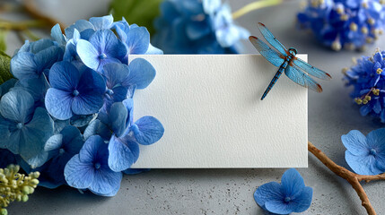 Blue flowers, a dragonfly, next to an empty white card.
