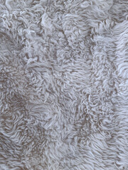 White faux fur texture close-up. High-resolution photo of soft, curly, and fluffy synthetic fur in light neutral tones. Ideal for cozy backgrounds, textile references, or winter-themed design.