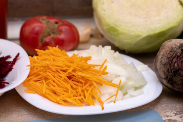 A vibrant assortment of fresh, raw vegetables, including shredded carrots, diced onions, and beets,...