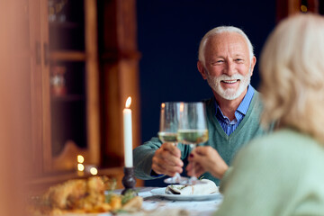 Elderly Couple Toasting With Wine During Cozy New Year Dinner At Home, Warm Ambience