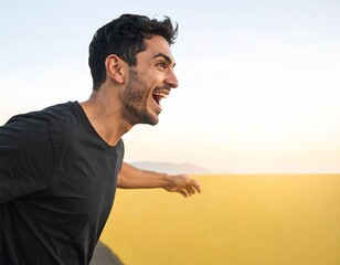 A young man in a black t-shirt laughs joyfully with his mouth open, looking towards the right, against a bright, sunny background.