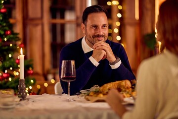 Man Enjoying Christmas Dinner With Wine, Candlelight, And Christmas Tree In Cozy Home Setting