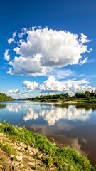 Naklejka premium Serene waters reflect a brilliant blue sky dotted with fluffy white clouds on a sunny day