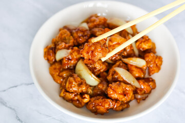 Eating delicious fried chicken smothered in a rich Teriyaki sauce with chopsticks.