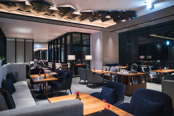 Contemporary hotel lounge in Japan shows plush seating, low wooden tables, and lamplight on glass...
