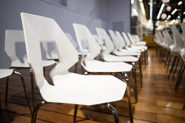 Clean modern white chairs neatly arranged in rows for professional meeting or event setup, ready for guests.