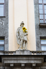 Obraz premium A Greek-style statue holding a sunflower on the facade of a stone building