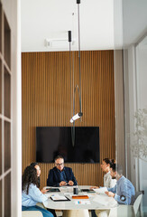 Multiracial colleagues working inside business office with glass walls - Entrepreneurs people sharing ideas at teamwork meeting - Brainstorming concept - Main focus on center man face - Vertical photo
