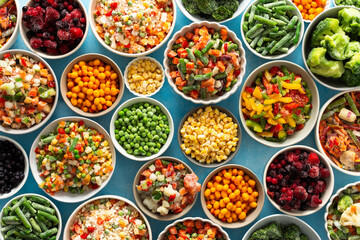 Fresh vegetables frozen in summer, neatly arranged in plates, ready for winter meals, showcasing vibrant colors and healthy options for future cooking, , vegetables in plates on a blue background