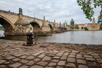 View of Charles Bridge over the Vltava River in Prague, Czech Republic, photographed from the riverbank on an overcast May day.