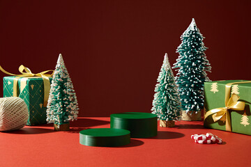 Christmas still life with trees, red podiums, and gold ornaments. Elegant and clean design background for advertising or design packaging mockups.