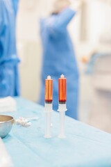 Two syringes filled with vibrant red solutions sit on a sterile table in a medical setting, showcasing advanced technology for cancer therapies targeting liver tumors
